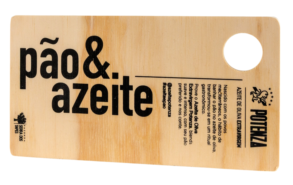 Tábua de servir retangular em madeira clara com a gravação em destaque "pão & azeite" em letras grandes pretas. A peça apresenta o logotipo do Azeite Potenza, o selo da Fazenda Serra dos Tapes e um breve texto celebrando o ritual gastronômico mediterrâneo de banhar o pão no azeite extravirgem.